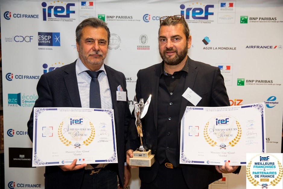 Deux hommes tenant des trophées et des certificats lors d'un événement.
