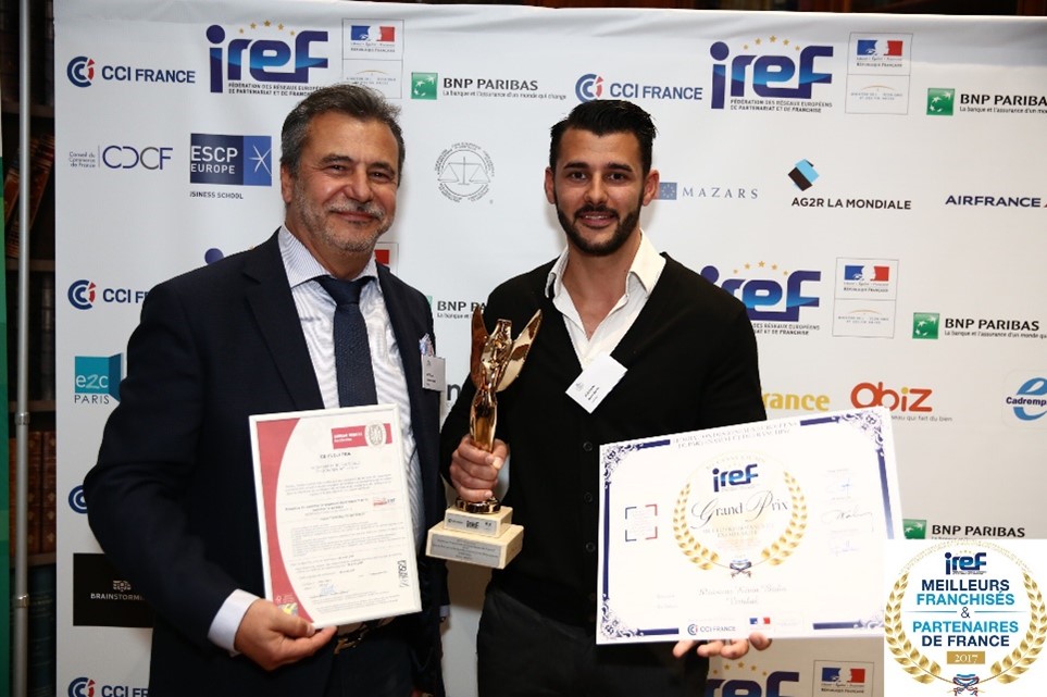 Deux hommes tenant des trophées et des certificats lors d'un événement.