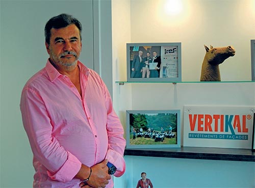 Homme en chemise rose devant des photos de chevaux