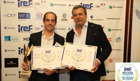 Deux hommes tenant des trophées et des certificats lors d'un événement.