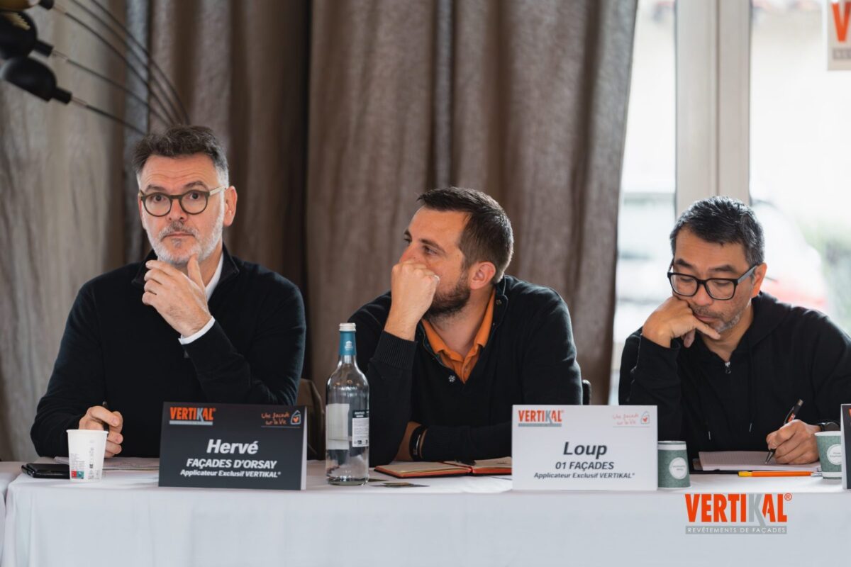 Trois hommes assis à une table de conférence, réfléchissant.