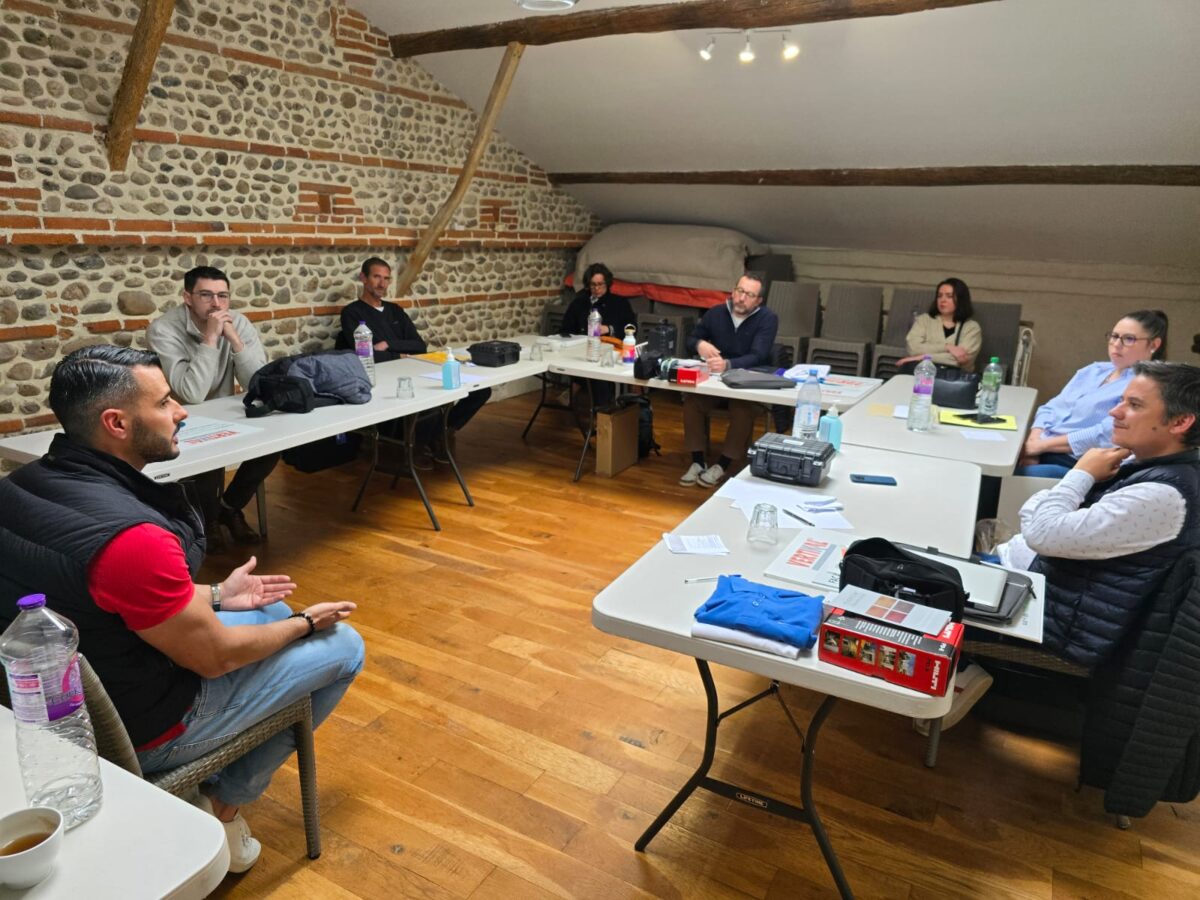 Groupe de personnes en réunion autour de tables.