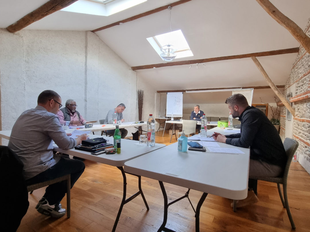 Hommes travaillant ensemble autour de tables avec des documents et des bouteilles d'eau.